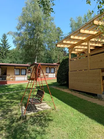 Dětské houpačky a pergola na trávníku areálu