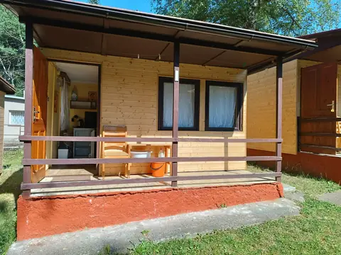 Řada dřevěných chatek s terasami v zeleni areálu